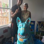 Two people with painted dog statue.