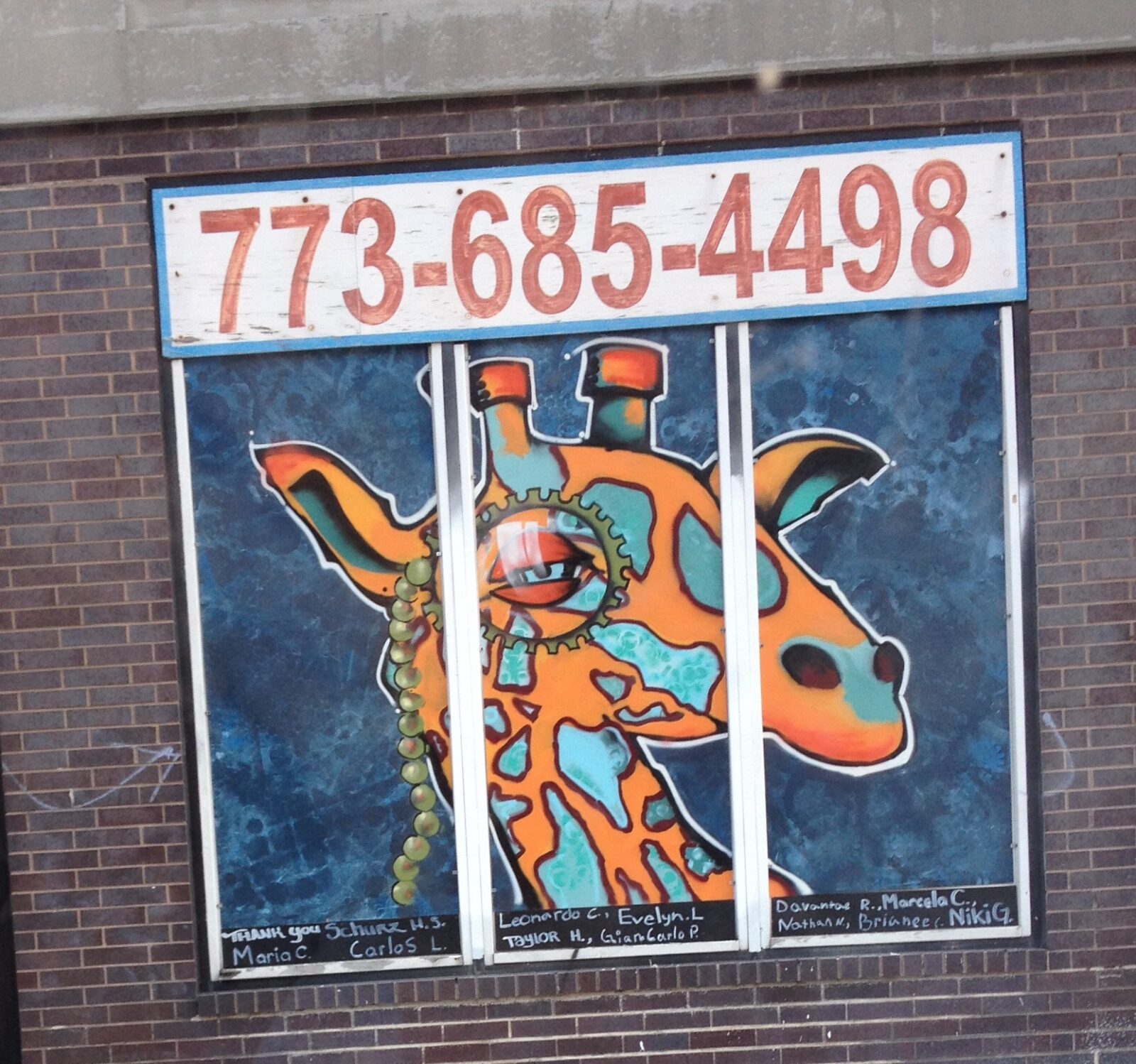 A giraffe painted on the side of a brick building.