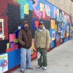 two men standing beside a wall mural