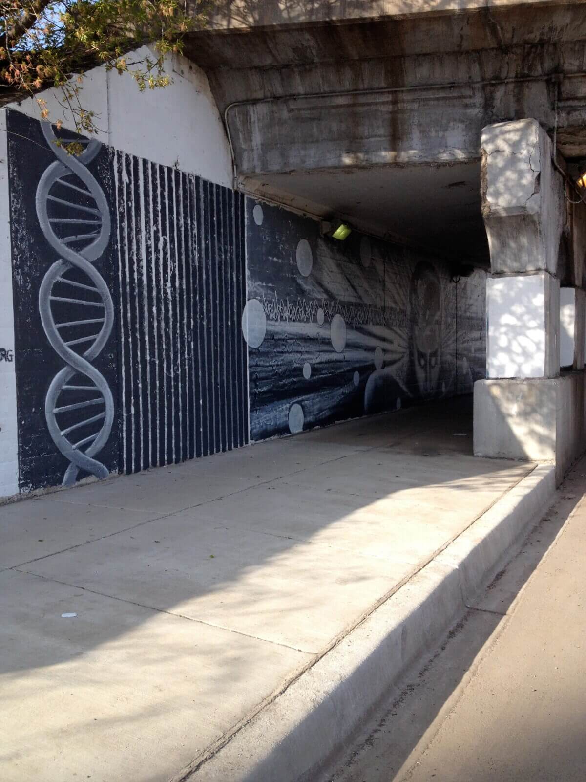 A black and white mural on the side of a bridge.