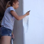 A girl is painting a wall with a paint brush.