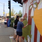 Two people painting a mural on a wall.