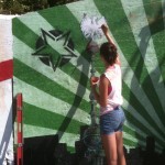 A woman painting a mural on a wall.