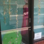 A woman in a dress is standing in front of a store window.