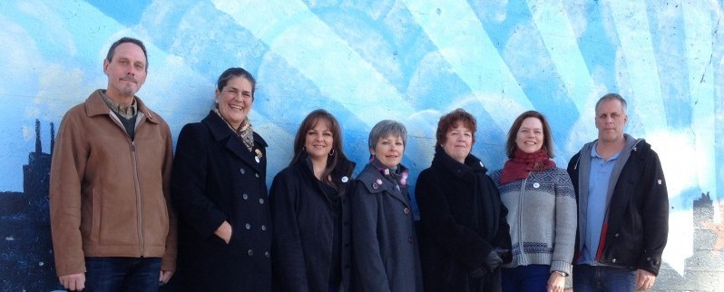 A group of people standing in front of a mural.