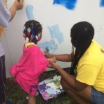 a child and adult painting a wall