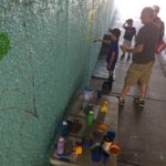 A group of people painting on a blue wall.