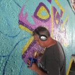 A man painting graffiti on a wall.