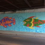 A colorful mural painted on the side of a bridge.