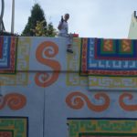 A man is painting a colorful mural on the side of a building.