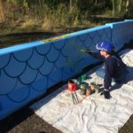 A man painting a blue wall.