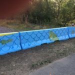 A blue barrier painted with frogs and crocodiles.