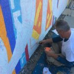 A man painting a mural on a wall.