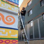 A man on a ladder painting a wall.