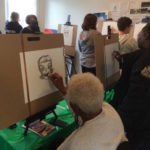 A group of people drawing on easels in a room.