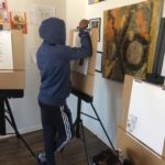 A group of children working on easels in an art studio.