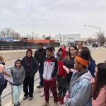 A group of people standing on a sidewalk.