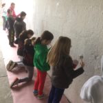 A group of children standing next to a wall.