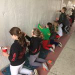 A group of children are painting on a wall.