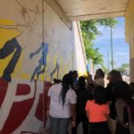 A group of people standing in front of a mural.