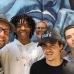 A group of people posing for a photo in front of a mural.