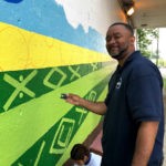 A man is painting a mural on a wall.