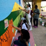 A group of people painting a mural on a wall.