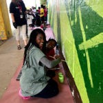 A group of people painting a mural on a wall.