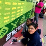 A group of children painting a mural on a wall.