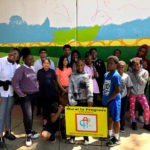 A group of children posing in front of a mural.