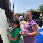 Three girls standing next to a white board with writing on it.