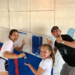 Three people are posing for a photo while painting a wall.