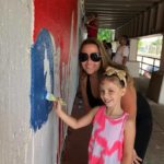 A woman and a little girl painting a wall.