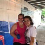 Two young women standing in front of a mural.