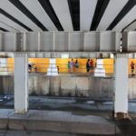 A group of people standing under an overpass.