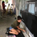 A woman is painting a mural in a tunnel.