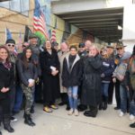 A group of people standing in front of a wall with american flags.