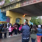 A group of people standing in front of a bridge.