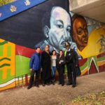 A group of people posing in front of a mural.