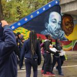 A group of people walking in front of a mural of martin luther king, jr.