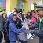 A police officer shakes hands with a group of children.