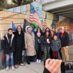 A group of people posing for a picture in front of a mural.