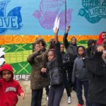 A group of people standing in front of a painted wall.