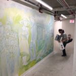 Artist painting a mural in a hallway.