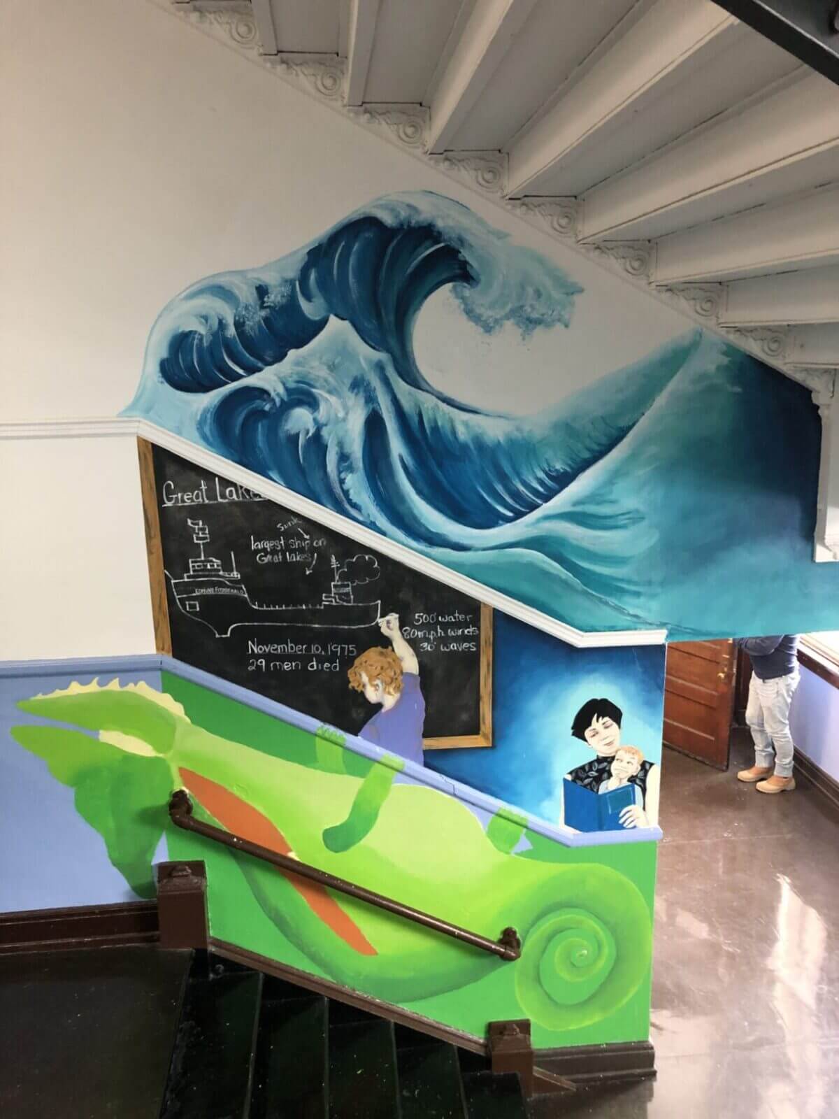 A mural of a wave on the stairs of a school.