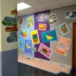 Colorful bulletin board with motivational posters and directional signs in a school hallway.